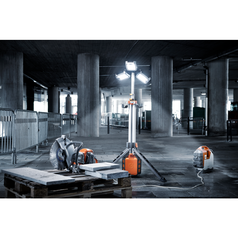 Construction site with a power cutter, work light, and vacuum cleaner on a concrete floor.