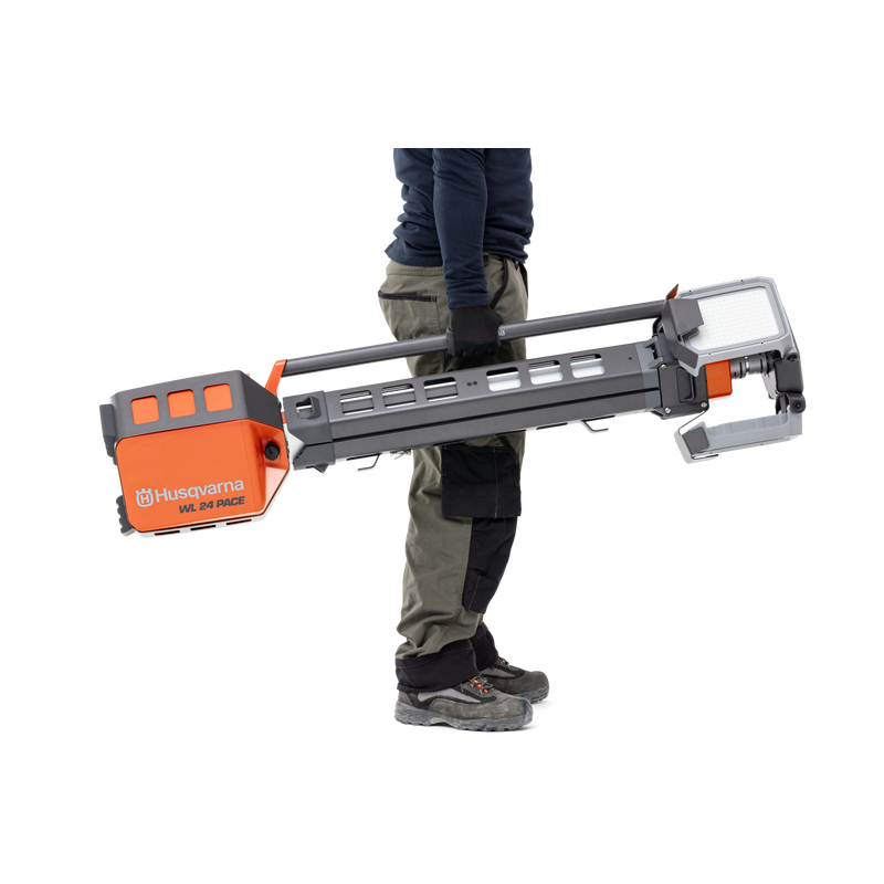 Person carrying a Husqvarna construction product, possibly a drill or cutter, in a studio setting.